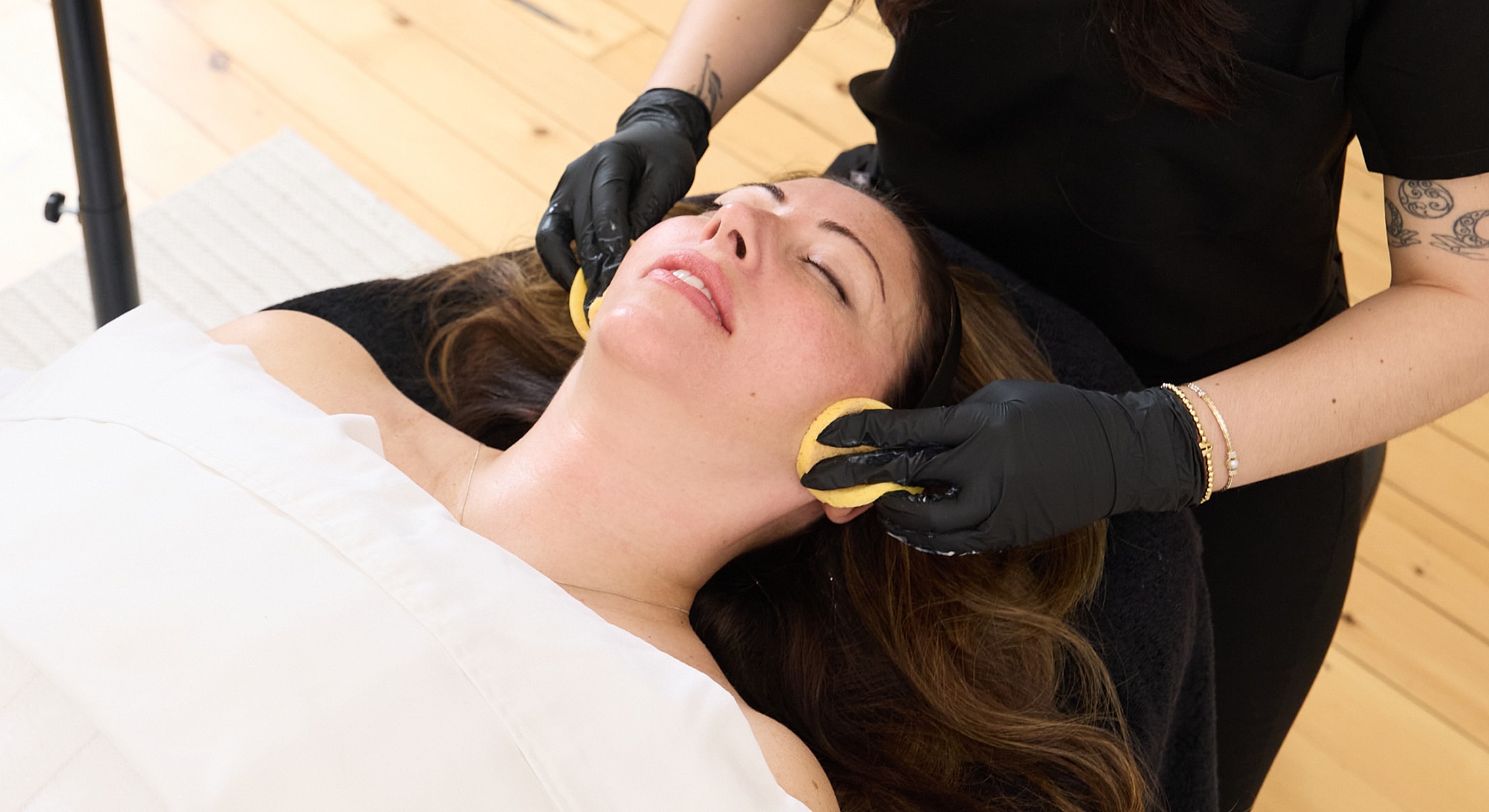 Woman receiving a facial treatment with sponges.