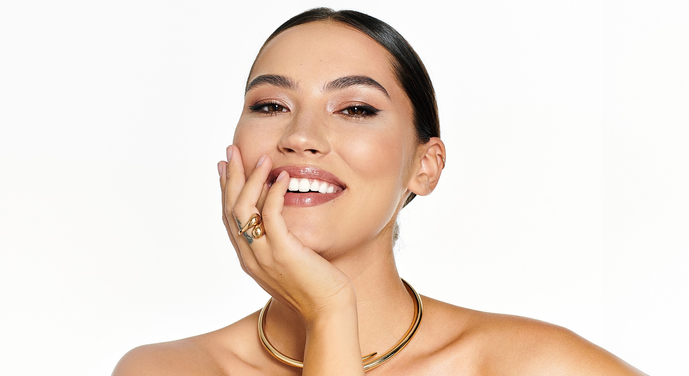 Smiling woman wearing jewelry against white background.